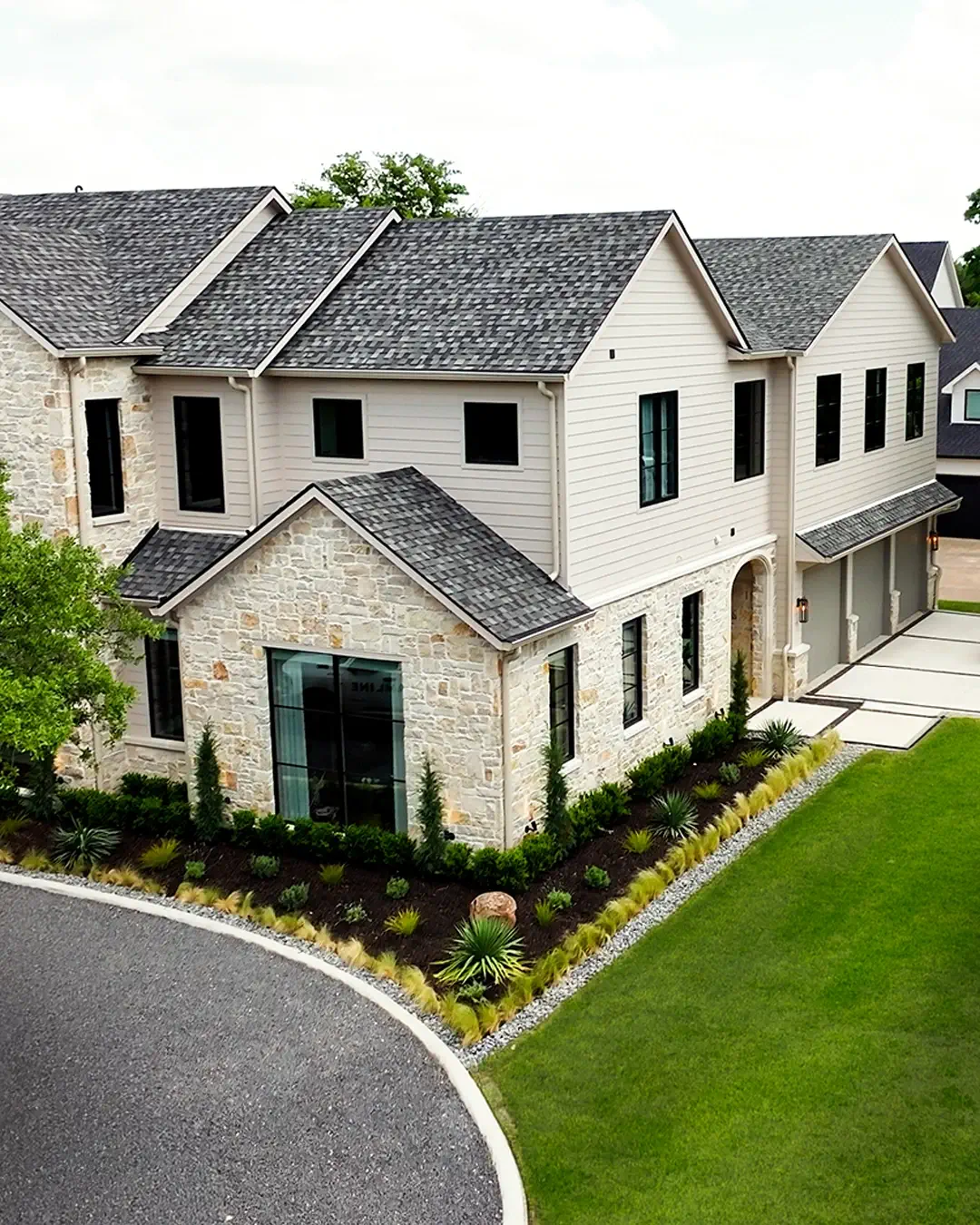 Front yard of a Colleyville stone home with newly installed planting beds, ornamental grasses, and a manicured lawn