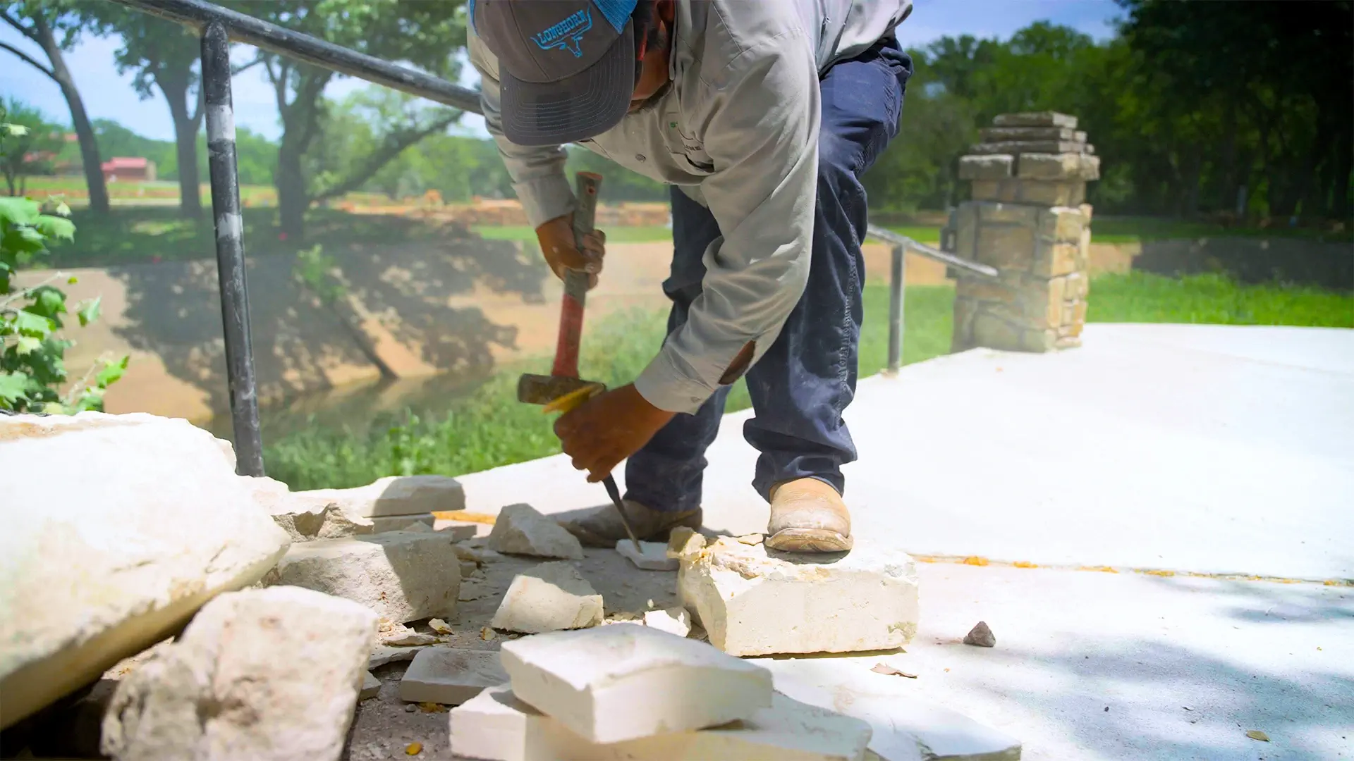 Mason splitting limestone blocks by hand with a hammer and chisel