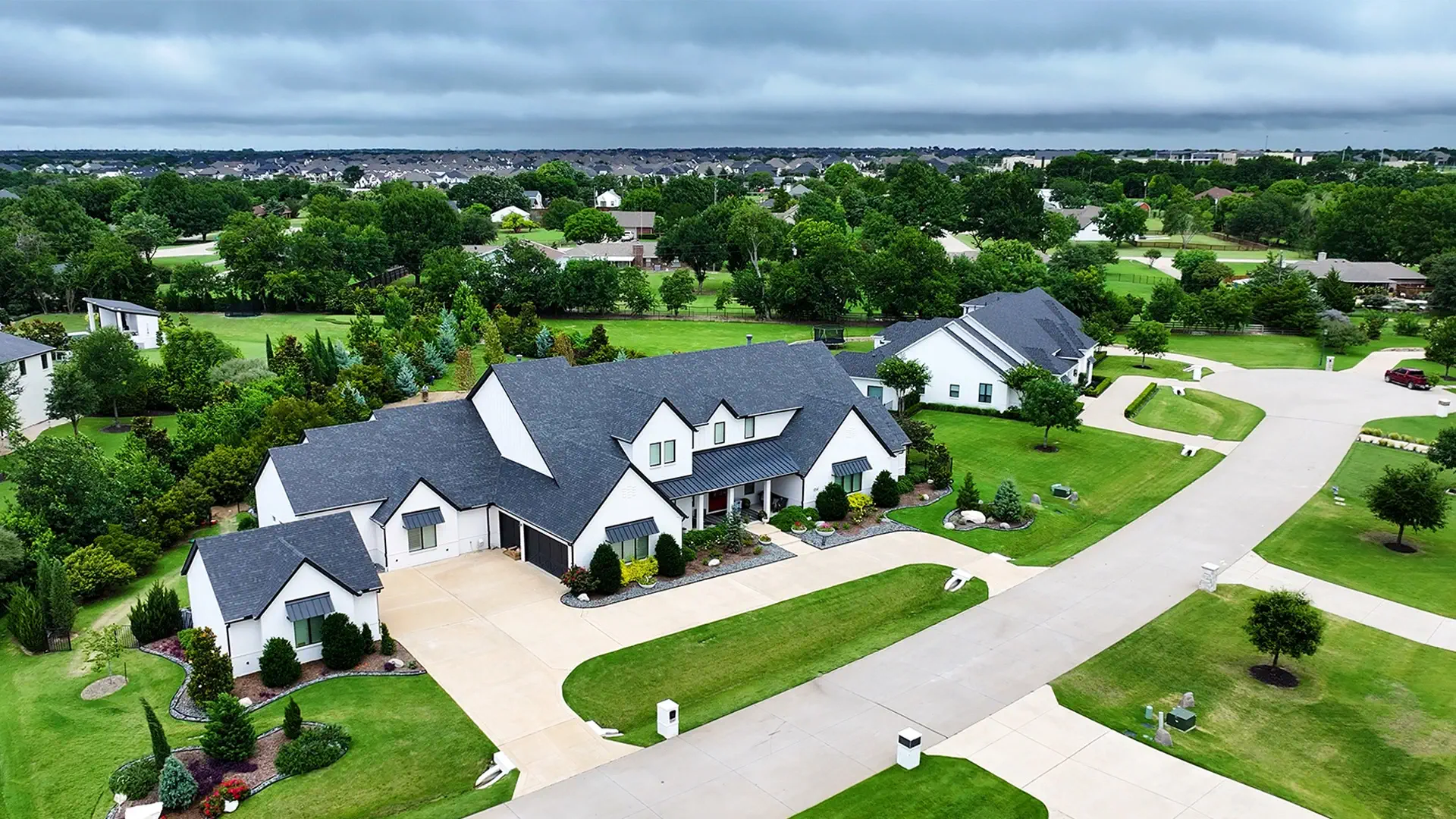 Aerial view of a professionally landscaped modern farmhouse front yard in North Texas with a manicured lawn and curated planting beds