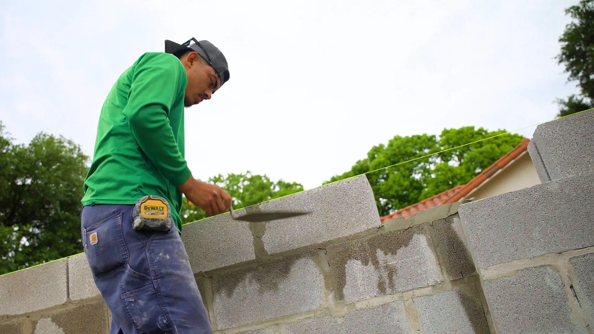 A mason spreading mortar along the top course of a block retaining wall