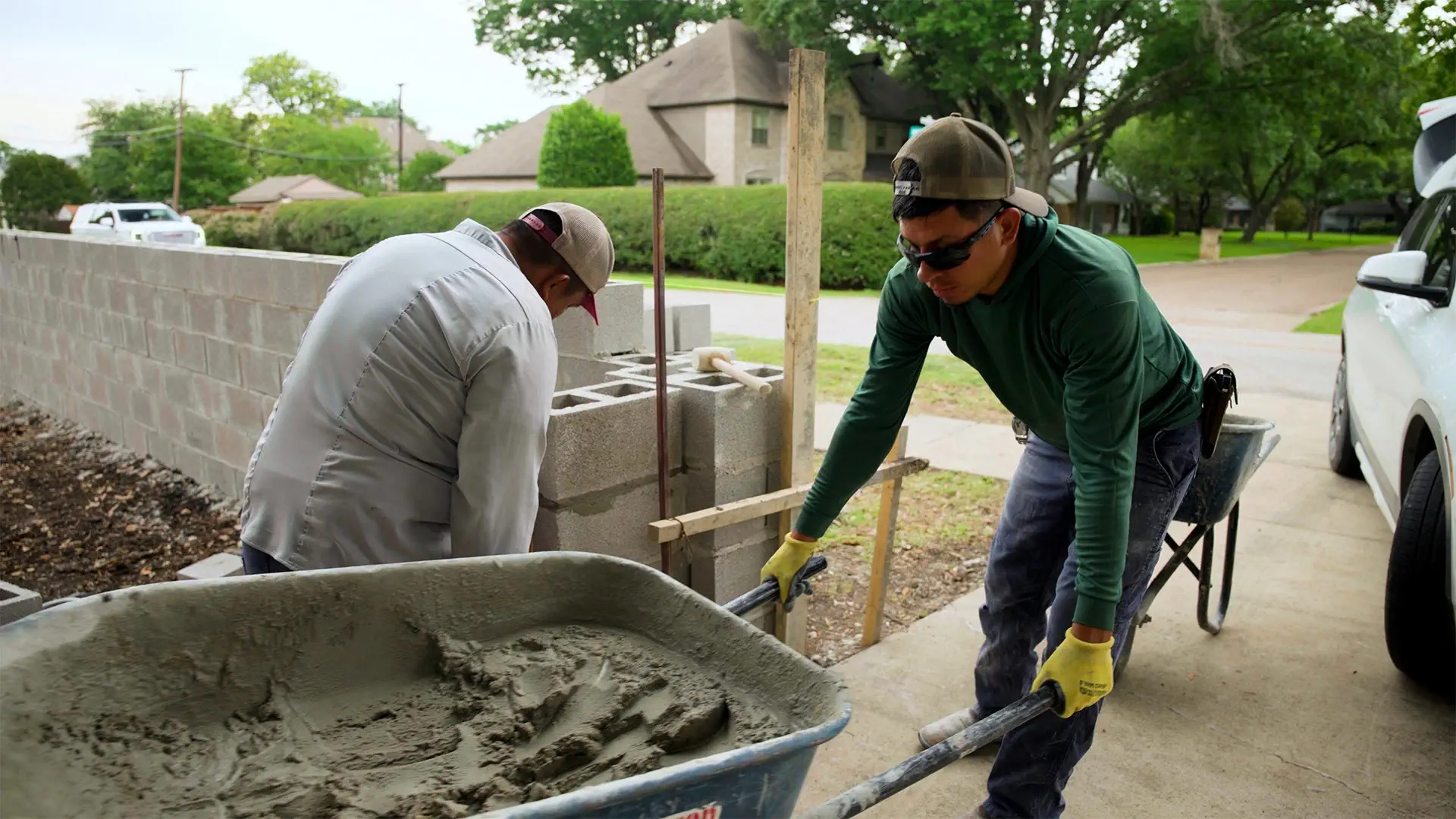 Landscape crew moving mortar by wheelbarrow while building a block retaining wall