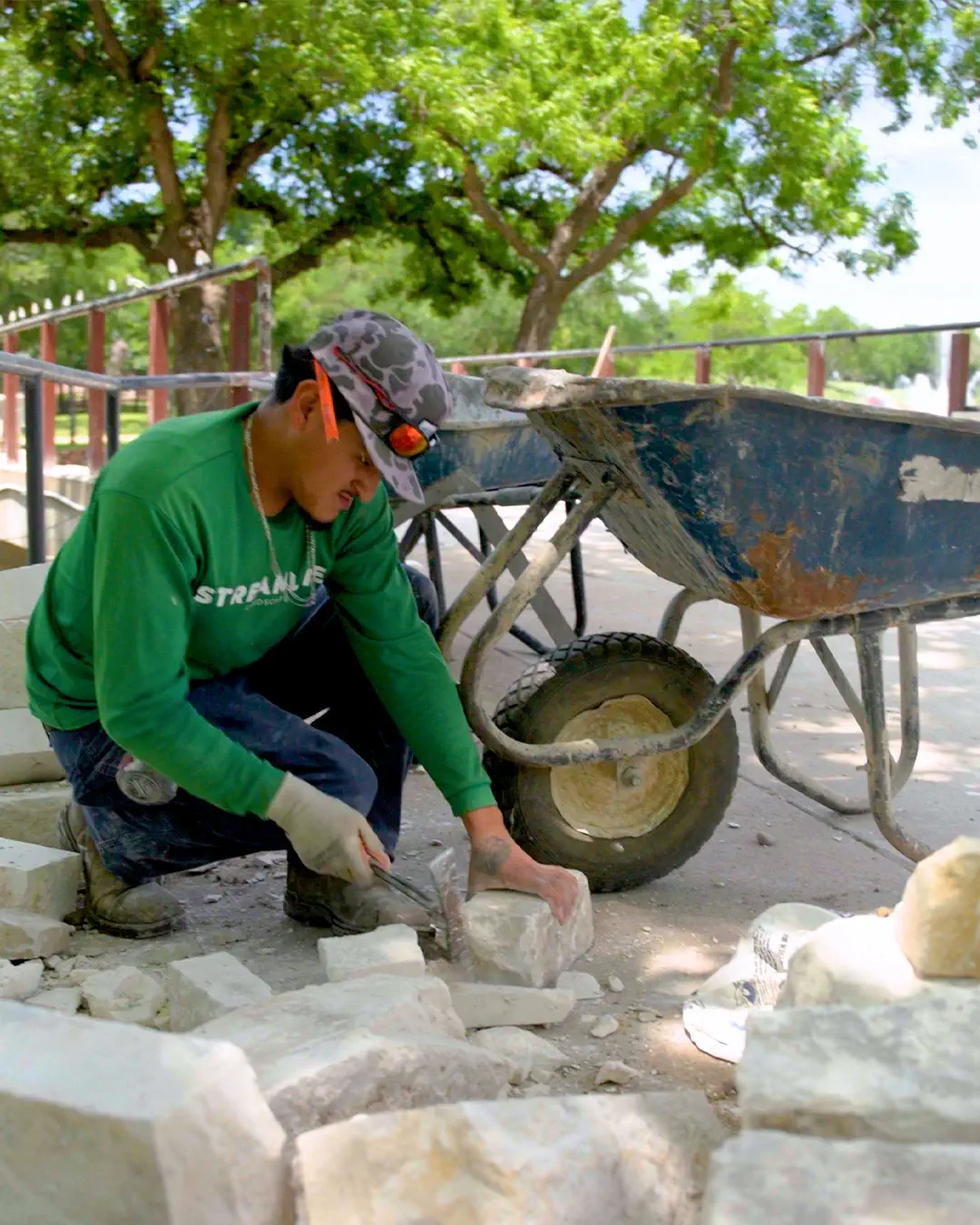 A Streamline Landscape mason dressing natural limestone along a stone walkway