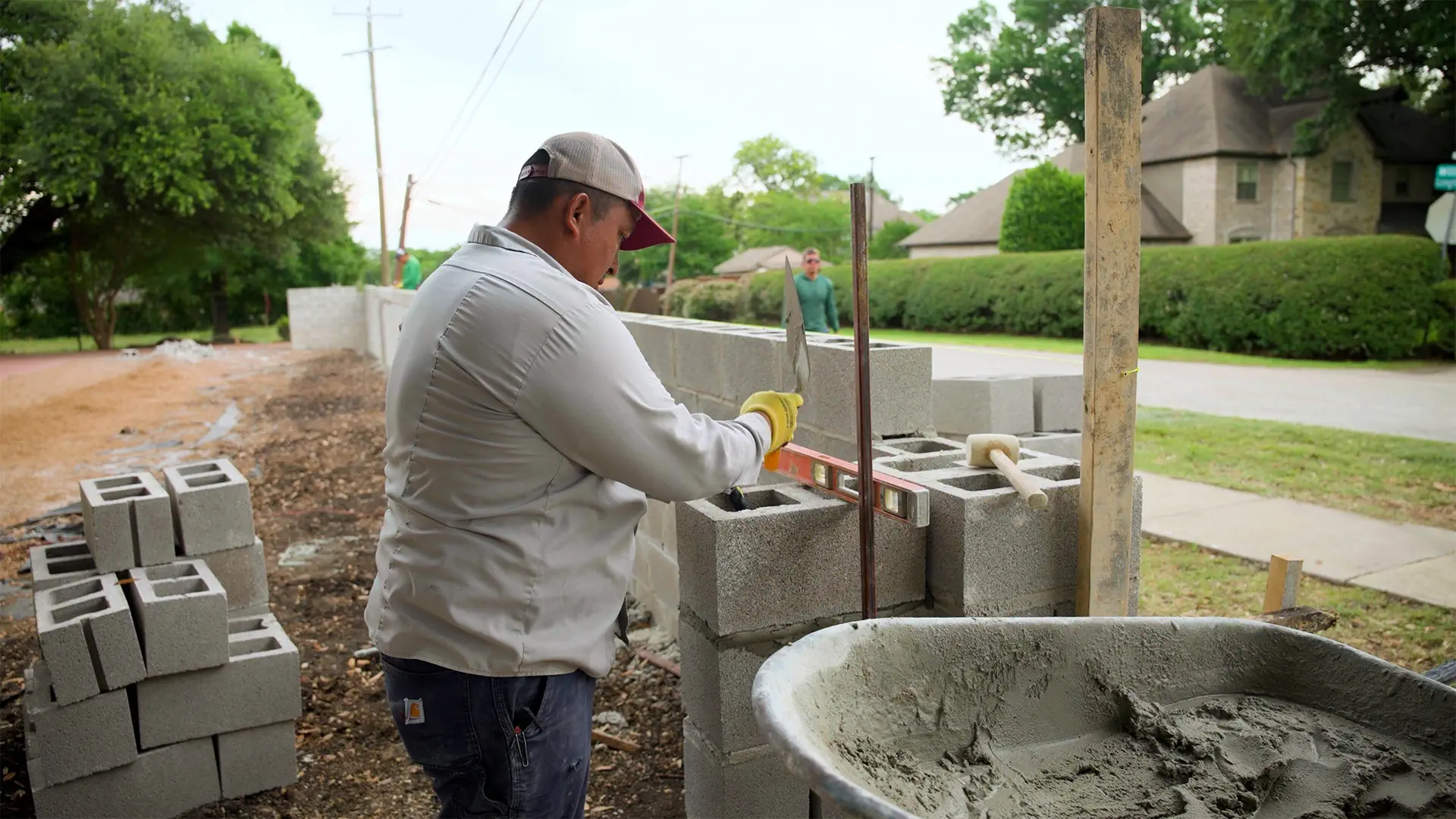 A mason leveling a block course while building a retaining wall on a North Texas project