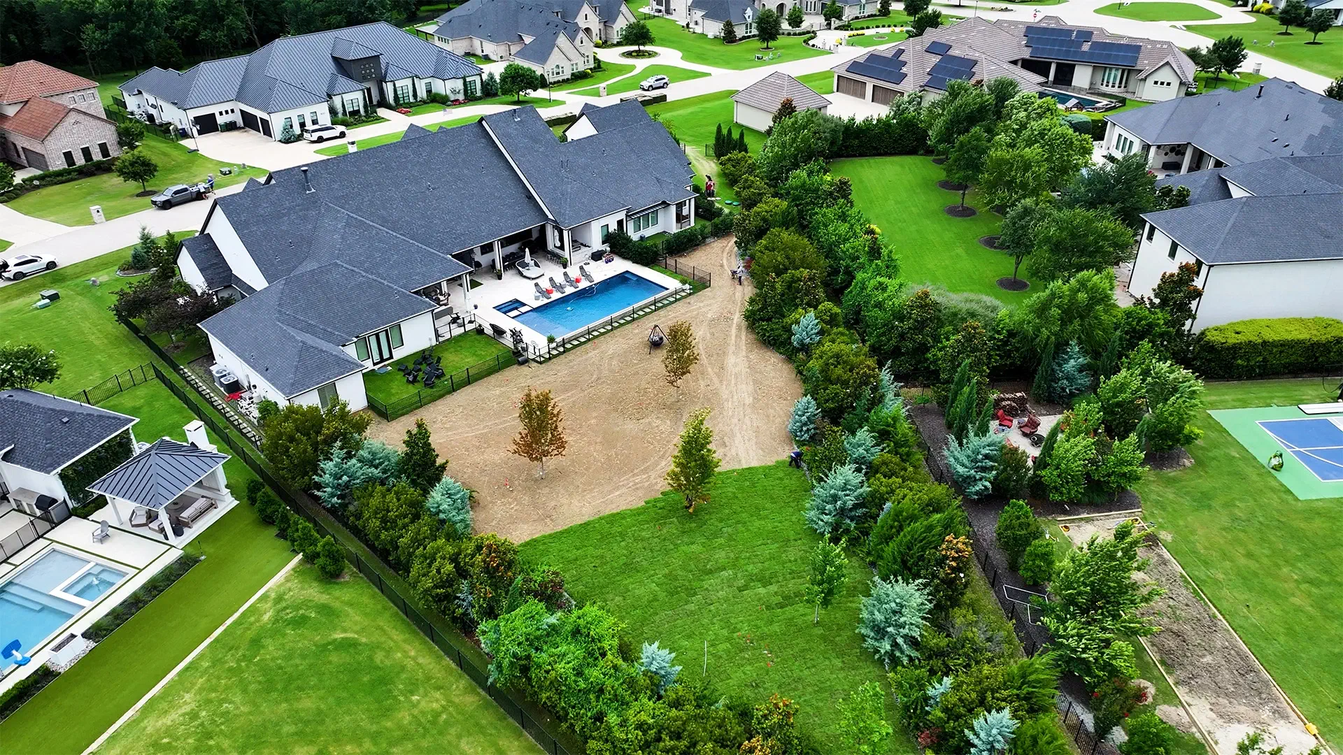 An aerial view of fresh sod going down across a graded North Texas backyard